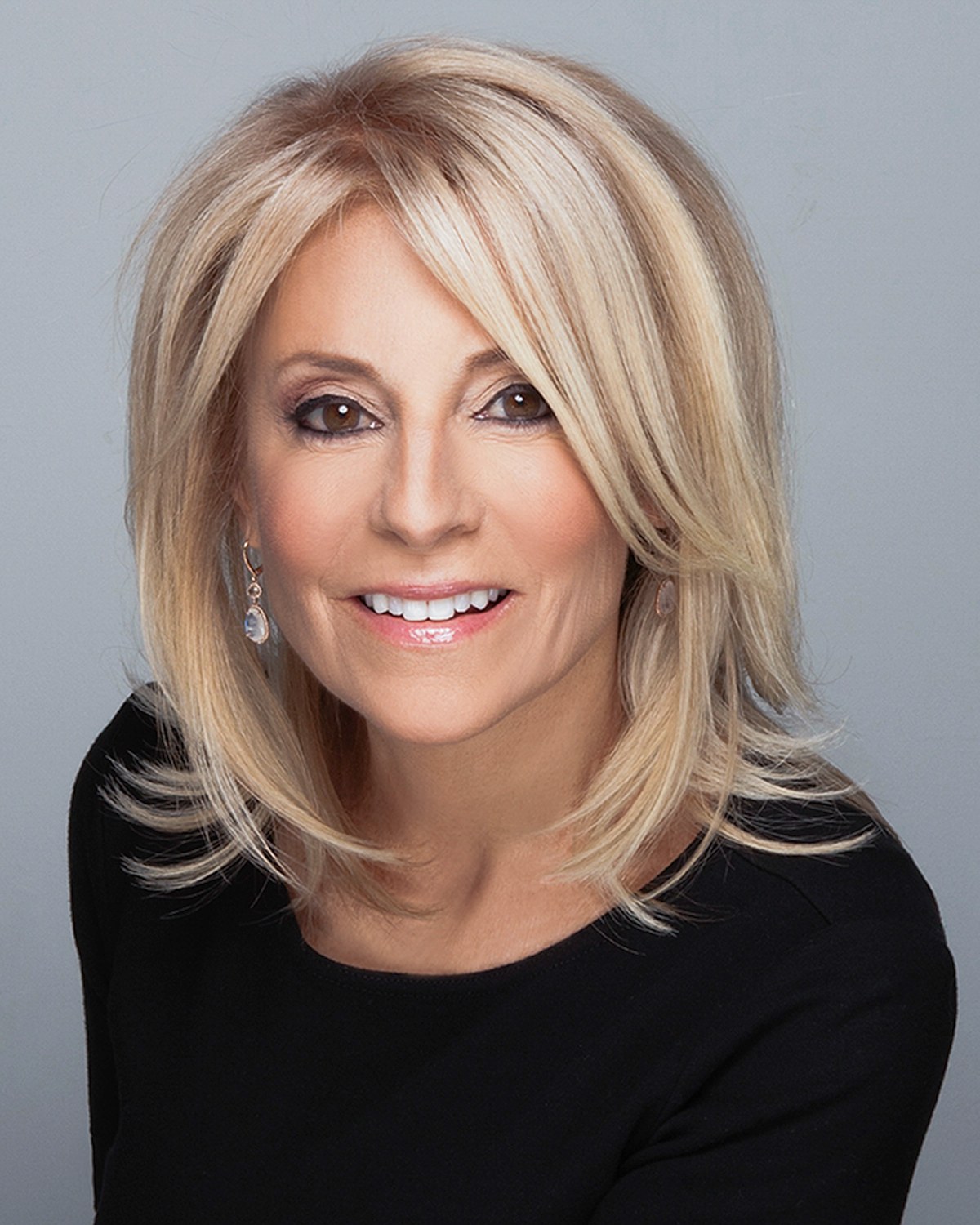Woman with blonde hair in a black top, close portrait, gray backdrop, photographed by Annie Watson in her Naples studio