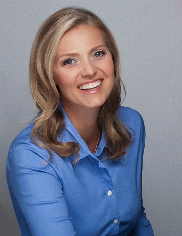 Woman with blonde hair in a blue button-down shirt, laughing, light gray backdrop, photographed by Annie Watson in her Naples studio